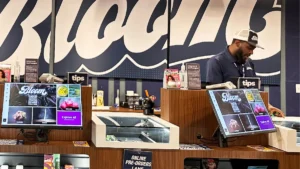 A budtender helping a customer choose a cannabis product at a dispensary counter.